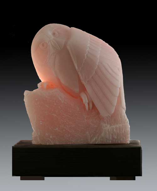 A photo of My Pink Hibou with a light behind it to show the stone's translucency
